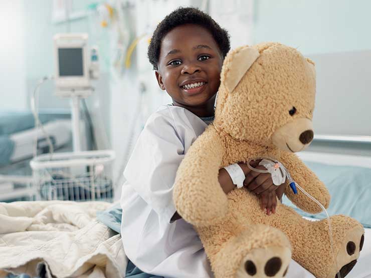 image of child holding teddy bear in hospital room